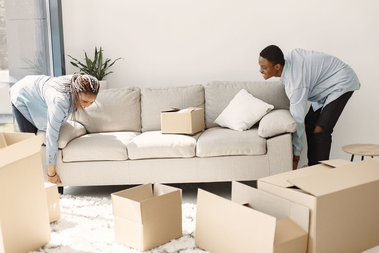 services-03 Happy couple setting up a sofa in their new home surrounded by moving boxes.